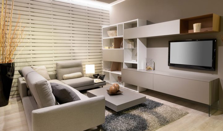 A contemporary living room showcasing custom white shelving units, a large flat-screen TV, and comfortable seating, all set against a backdrop of stylish, ambient lighting.