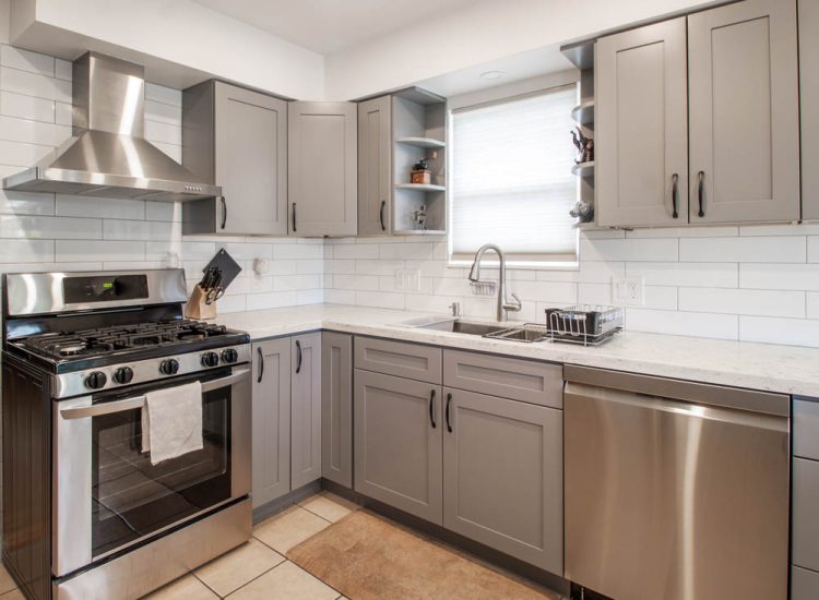A modern kitchen design with gray cabinetry, white subway tiles, and stainless steel appliances, offering a sleek and functional cooking environment with ample natural light.