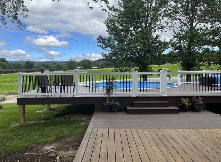 A spacious wooden deck featuring a serene pool area and outdoor seating, offering panoramic views of the surrounding countryside, ideal for relaxation and gatherings.