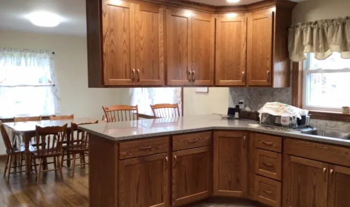 A spacious kitchen area with wooden cabinets and a central island topped with granite. The dining table is adjacent to the kitchen, providing a seamless flow between dining and cooking areas.