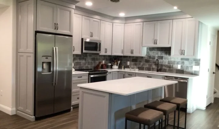 This beautifully designed kitchen showcases sophisticated gray cabinetry, a stylish stone backsplash, and a spacious island, offering a luxurious space for culinary adventures.