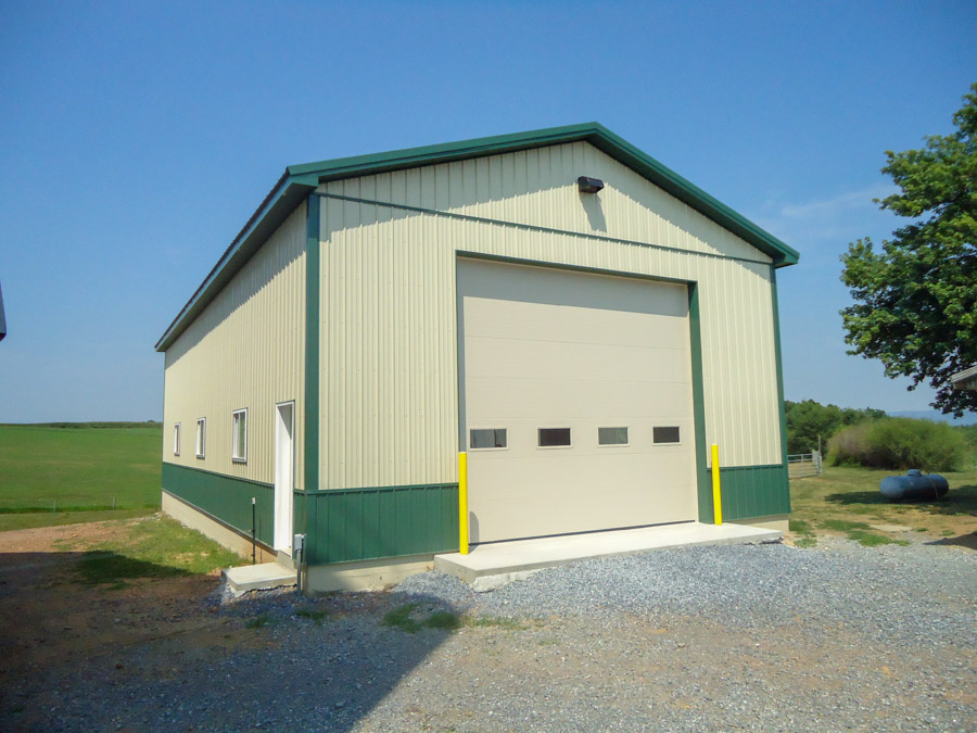Tan pole building with green trim and a large overhead door built by Leids Carpentry
